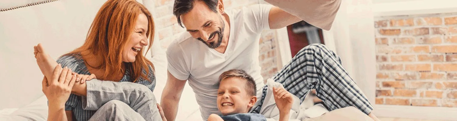 Familie lacht gemeinsam im Bett
